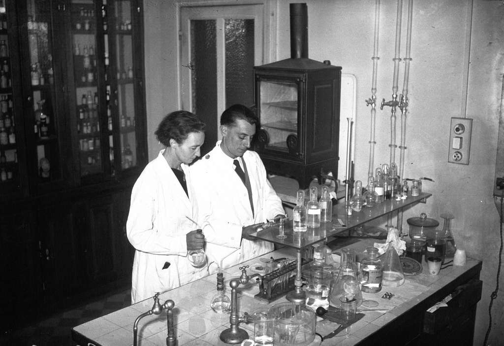 Irène e Frédéric Joliot-Curie nel loro laboratorio nel 1935.
Immagine in pubblico dominio. 
Fonte: Bibliothèque nationale de France